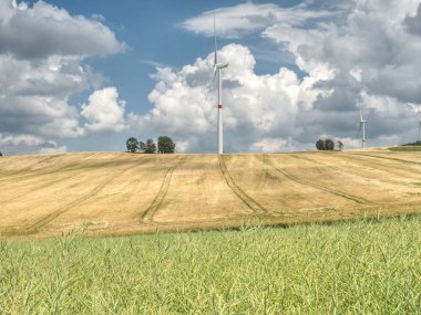 Yeşil alanda güneşli bir günde büyük yel değirmenleri. Ücretsiz enerji