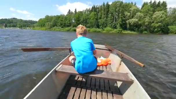 若い十代の少年は 銀行で森と湖に手漕ぎボートやパドルボートを漕ぐ 背景に青い夏の空 — ストック動画