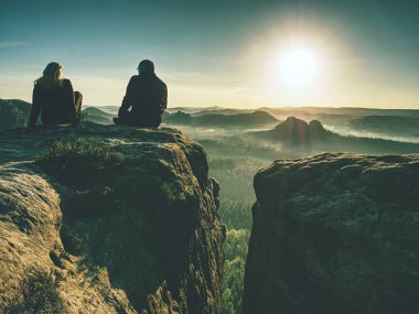 İki yürüyüşçü fotoğraf çekiyor ve dağın tepesinde konuşuyorlar. İki fotoğrafçı 