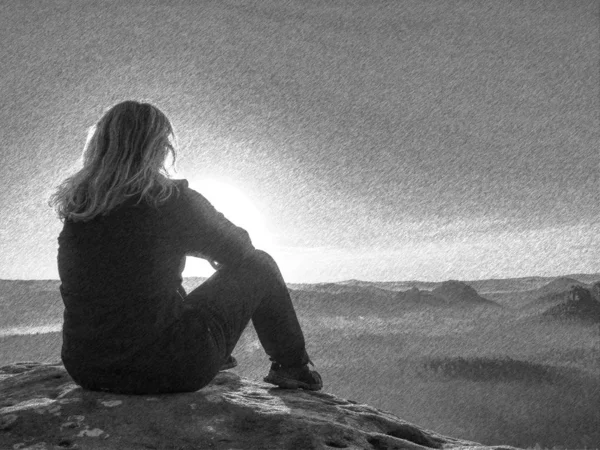 Chica sentada en una piedra junto a los picos bajo los rayos del sol — Foto de Stock