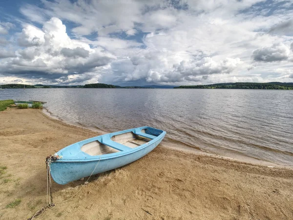 Blue fishing boat anchored on beach sand of lake. Smooth level — Stock Photo, Image