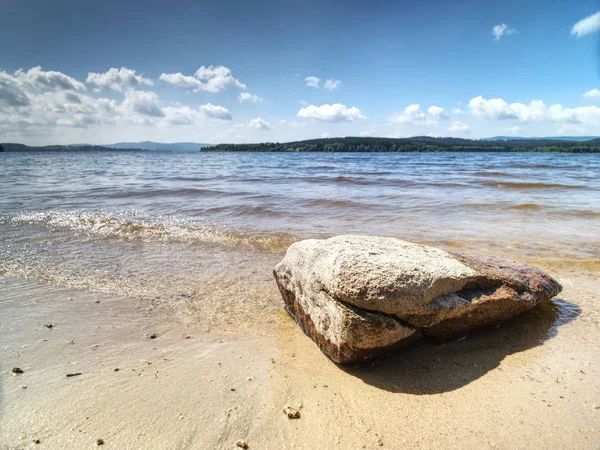 Uma pedra solitária na areia da praia perto da água do lago. Detalhe — Fotografia de Stock