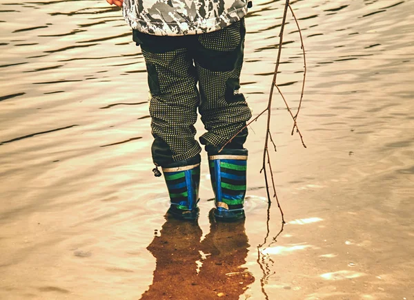 Crianças pequenas com botas de borracha caminham em água lamacenta suja — Fotografia de Stock