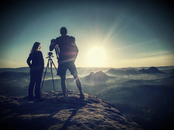 Amigos fotógrafos discutir e tirar fotos contra o pôr do sol — Fotografia de Stock