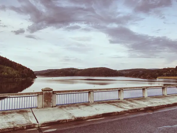 View over foot bridge handrail to dam water level. Evening sky — Stock Photo, Image