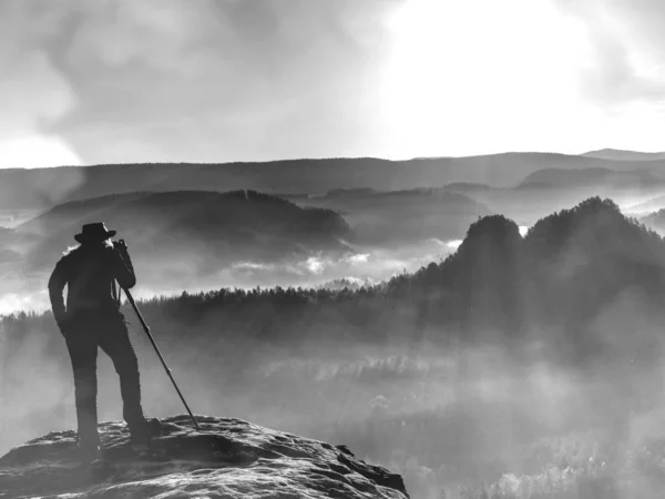 Turista com câmera fotografa nascer do sol enquanto está em pé no topo da montanha — Fotografia de Stock