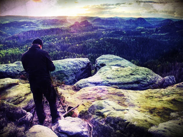 Turista com câmera fotografa nascer do sol enquanto está em pé no topo da montanha — Fotografia de Stock