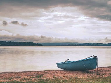 Yalnız balıkçı teknesi sakin gölde sahile demirledi. 