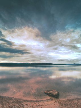 Göl suyuna yakın kumda yalnız bir taş. Ayrıntı