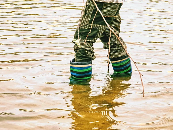 Criança usando botas de chuva em pé em poça de lama — Fotografia de Stock