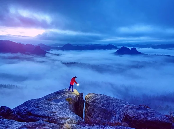 Chica en el borde rocoso por encima de la nube de niebla iluminado mundo brumoso —  Fotos de Stock