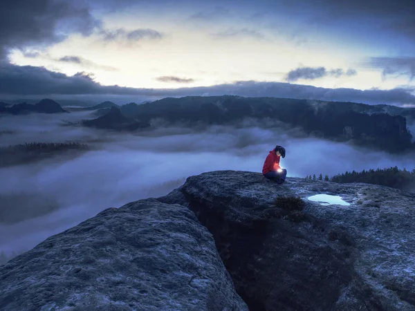 Wandermädchen sitzen in dunkler Nacht über Wolken und warten auf den Sonnenaufgang — Stockfoto