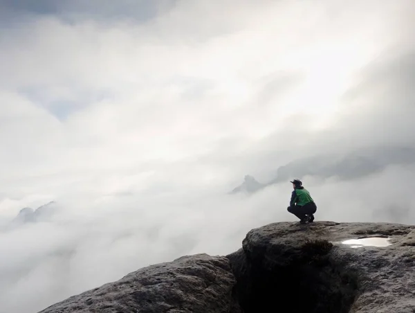 Man sitting on cliff enjoying mountains and clouds landscape — Stock Photo, Image