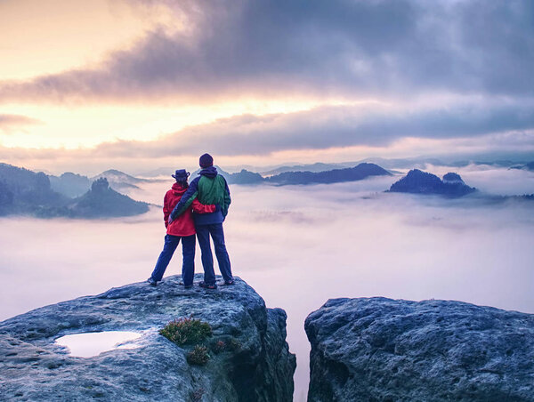 Couple on mountain looking over heavy mist to  horizon