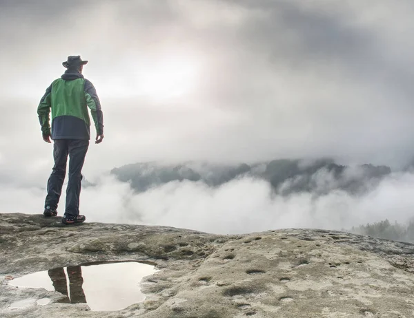 Hiker watching over misty valley to blurred horizon in thick fog — Stock Photo, Image