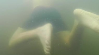 Göle dalmak. Suyun altında yüzen çocuğu takip eden çıplak vücut sadece ıslak pantolon giyer.. 