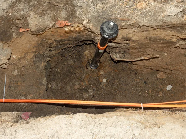 Water supply valve and lines of metallic and fiber optic cables. The trench carries the conduits for gas water electric sewage and phone services