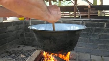 Aşağıdan yukarıya bak ve kızarmış soğan kazanının içine bak. Büyükbaba tahta kaşıkla kazanda kıpırdıyor. Yavaş çekim.