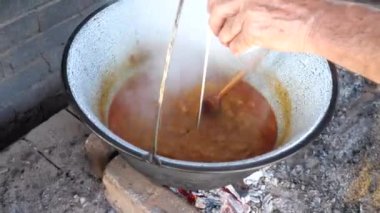 Şef, domuz kebabına tuz döküyor. Bahçe sobasında, derin emaye ısıtıcısının içine. Geleneksel aile yemeğinin bahçe yemeği