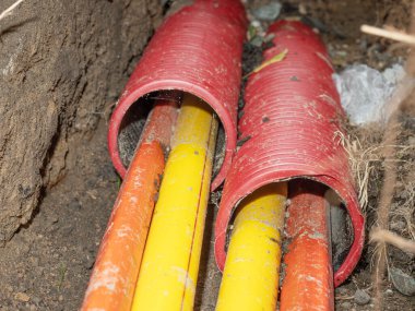 Sarı ve turuncu plastik optik veri lifleri kırmızı başlıklı HDPE tüpünden geçiyor. İnternet sağlayıcısı hgh hız bağlantısının yeni ağını oluşturuyor.
