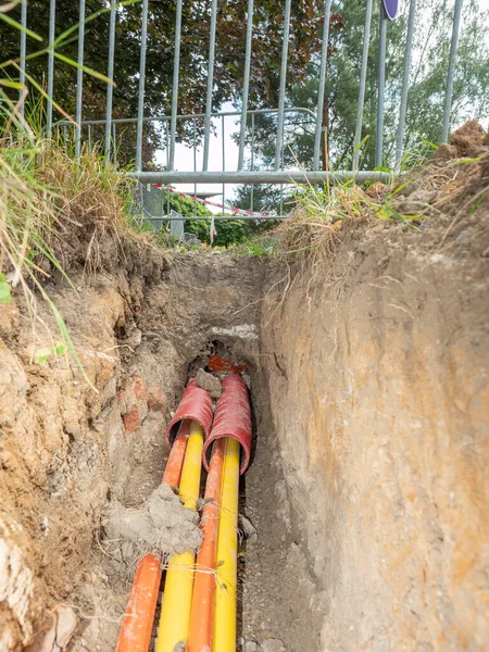 Yellow and orange plastic cores of optic data fibers go through red ribbed HDPE tube. Internet provider building new net of hgh speed connection.