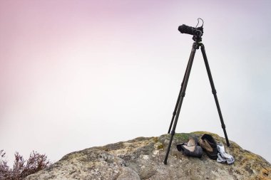 Tripodun üzerinde modern profesyonel kamera, vahşi hayatta açık hava fotoğrafçılığı. Dağlar arka planda. Bir tridop üzerindeki kamera bir dağ manzarasının fotoğrafını çeker.