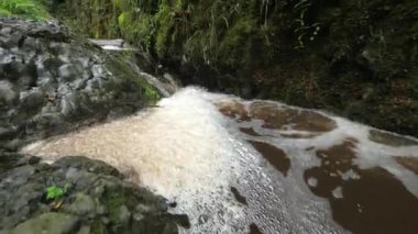 Kahverengi köpüklü hızlı akış. Şelaleden ya da şelaleden akan çamurlu su büyük kabarcıklardan adalar oluşturur..