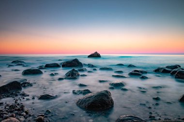 Kayalık bir kıyıya vuran köpüklü dalgalarla uzun deniz manzarası