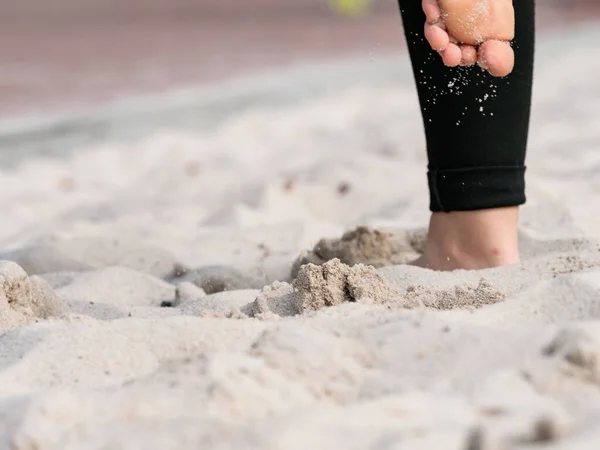 Sand grains fly as beach volleyball players run and jump at the net.