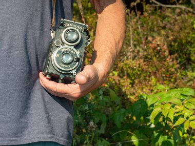 Eski fotoğrafçı analog kamera kullanır. Kıdemli adam yaz doğasında rahatlar. Voigtlander 'ı tutan adam muhteşem bir kamera ve doğada fotoğraf çekiyor.