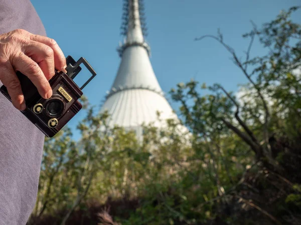 旅行中の老人の手はヴィンテージフィルムカメラを保持します 夏の日の間にタワーと年金受給者の訪問山 — ストック写真