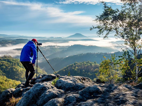 Outdoor travel photographer journalist holding a dslr camera in mountain background. Man takes photo of nature and environment theme