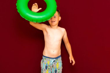 Yaz tatili konsepti, mutlu beyaz çocuk öğrenci portresi çıplak mayo yeşil şişme yüzük yaz tatilinde eğlenen çocuk, kırmızı arka plan..