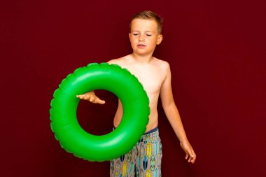 Yaz tatili konsepti, mutlu beyaz çocuk öğrenci portresi çıplak mayo yeşil şişme yüzük yaz tatilinde eğlenen çocuk, kırmızı arka plan..