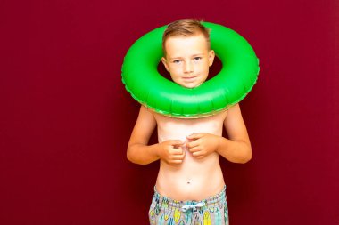 Yaz tatili konsepti, mutlu beyaz çocuk portresi çıplak çocuk şortu sırılsıklam mayo çocuk yaz tatilinde eğleniyor, stüdyo çekimi kırmızı arka plan.