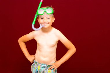 Çocuk kırmızı arka planda dalış maskesi reklamları yapıyor. Seyahat ve yaz konsepti