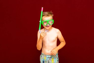 Çocuk kırmızı arka planda dalış maskesi reklamları yapıyor. Seyahat ve yaz konsepti