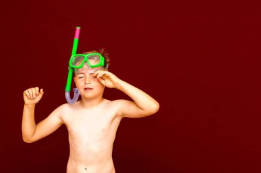 Dalış reklamlarından sonra kırmızı arka planda dalış maskesi takan çocuk. Seyahat ve yaz konsepti