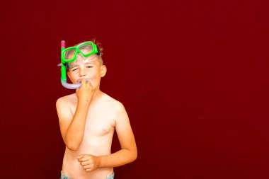 Çocuk kırmızı arka planda dalış maskesi reklamları yapıyor. Seyahat ve yaz konsepti