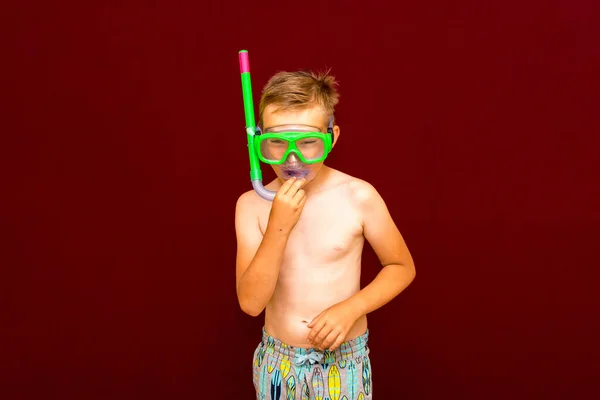 その少年はダイビングの準備ができている 赤の背景にダイビングシュノーケリングマスクを広告しています 旅と夏のコンセプト — ストック写真
