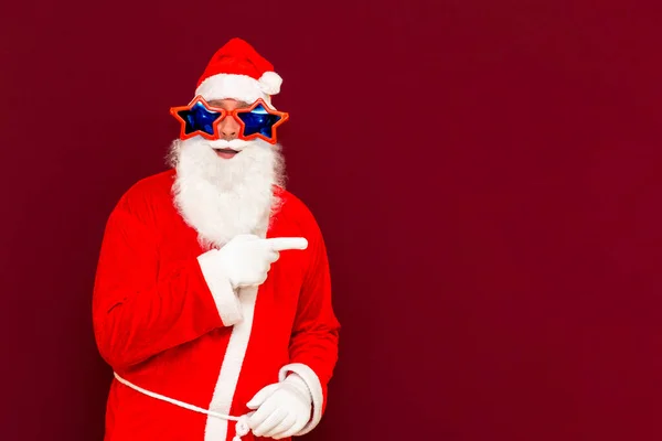 산타클로스 복장의 머리쓰개와 턱수염이 모양의 안경이 배경에 현수막을 있음을 나타낸다 — 스톡 사진