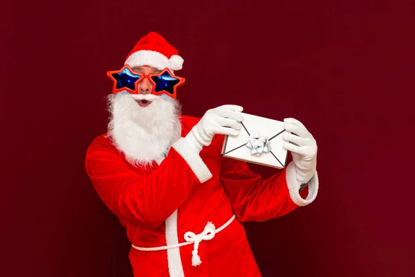 ギフト配送サービス サンタクロースの帽子の偽髭の男はギフトレター封筒ボックスを保持しています クリスマスや新年の休日 男のクリスマスのギフトボックス サンタクリスマス男保持ギフトプレゼント — ストック写真
