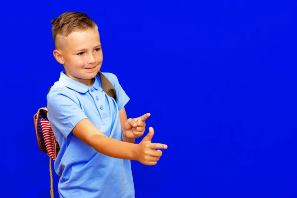 Ung Skolpojke Blå Skjorta Ryggsäck Pekar Fingrar Arbetsyta Isolerad Klarblå — Stockfoto