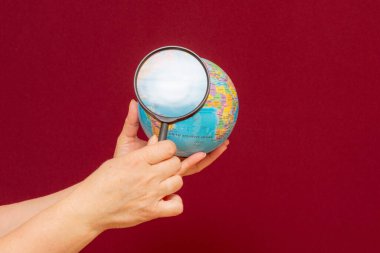 Bir elin bir dünya küresi üzerinde büyüteç tutmasının kavramsal görüntüsü.