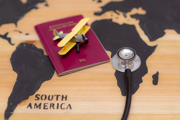 木製世界地図上の聴診器パスポート文書やおもちゃ飛行機と医療旅行の概念のトップビュー背景 — ストック写真