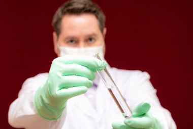 Laboratuvar önlüklü veya laboratuvar önlüklü bilim adamlarının üzerlerinde reaktif bulunan test tüpleri, kimyasal sıvı içeren laboratuvar camları, biyokimya laboratuarı araştırmaları. Burgundy renk arkaplanı..