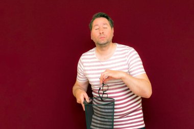 Son moda, çekici, orta yaşlı adam gözlerini kapadı. Çizgili tişört giymiş adam, şarap rengi arka plandaki çöp kutusuna bardak attı..