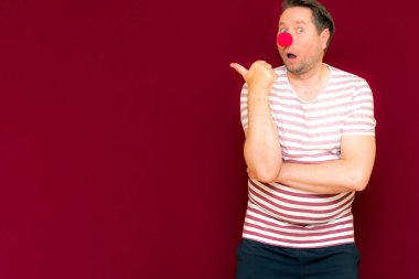 Mutlu, büyüleyici, modaya uygun ve gülümseyen adam şovları yan yana ya da uzay bordo duvarının kopyası. Kırmızı burun günü ya da Nisan 1. Palyaço, eğlence, parti, kutlama, eğlence, eğlence, tatil, mizah konsepti