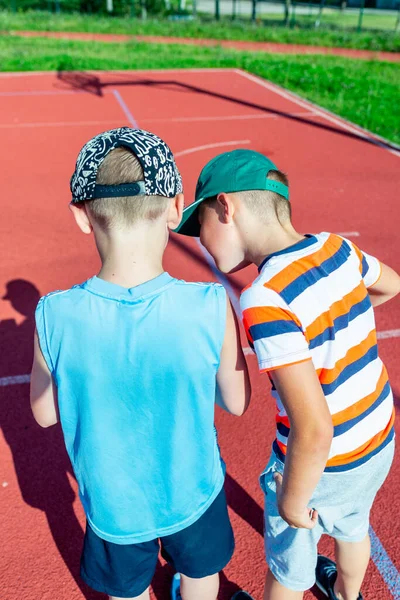 Çekici beyaz tenli iki küçük basketbolcu açık havada antrenman yapıyor.