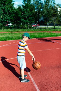 Telsiai, Litvanya 08: 12 2020 Çekici Kafkasyalı küçük basketbolcu açık havada kırmızı kortta antrenman yapıyor.